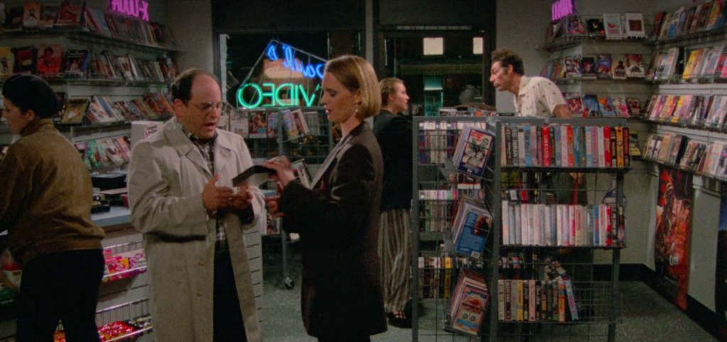 screenshot from the show Seinfeld with George, Susan and Kramer in a video rental store.
