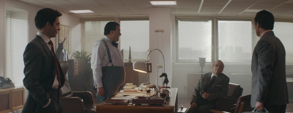 a group shot of Kevin and Robert Maxwell on one side of a desk, Stein and Rogers on the other