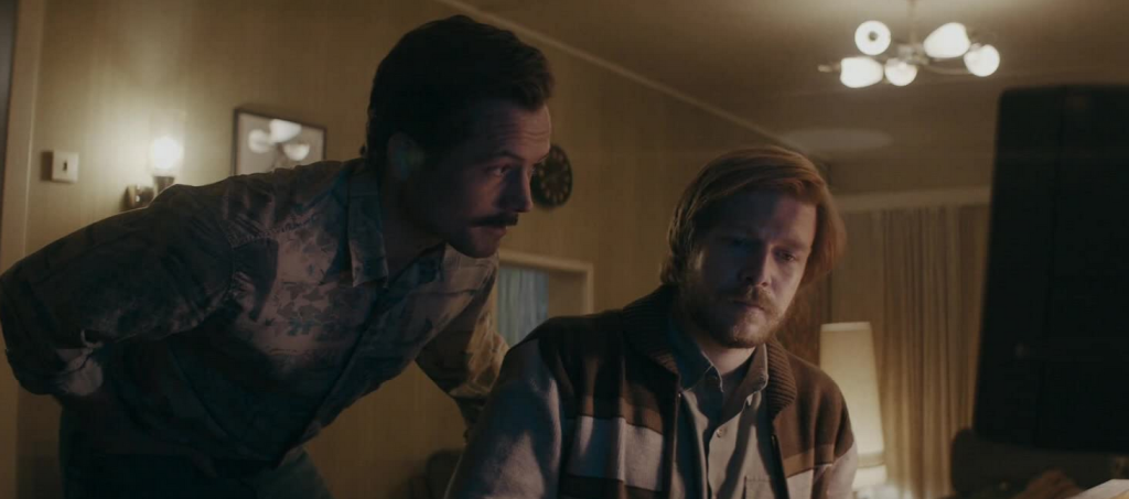 a still from the Tetris movie of Rogers and Pajitnov leaning over an old computer screen