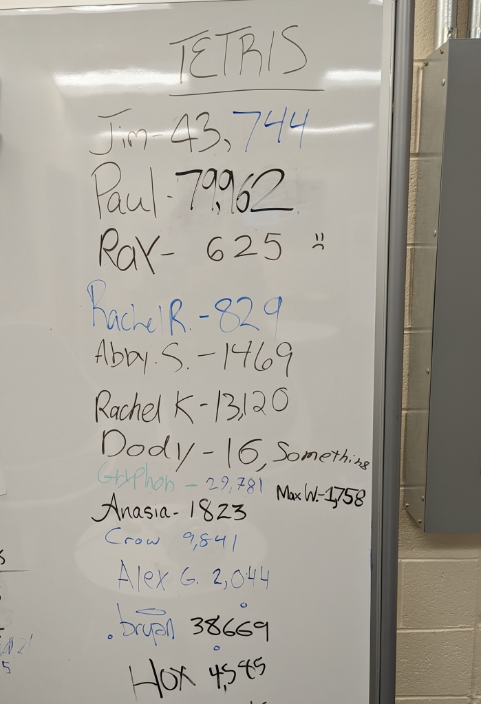 whiteboard with a Tetris written at the top, underneath is a bunch of names with high scores next to them.