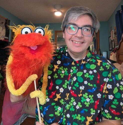 me holding an orange puppet with yellow yarn arms